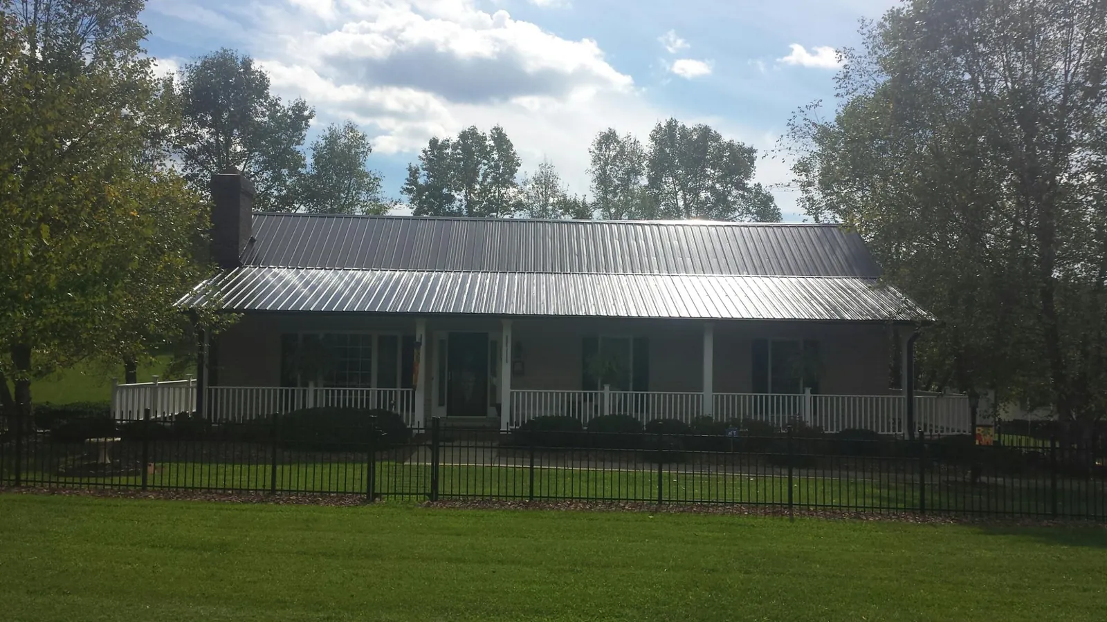 Gray metal roof on a brick ranch with a full width front porch — Gutter Guard Installation work by our crew in Lancaster